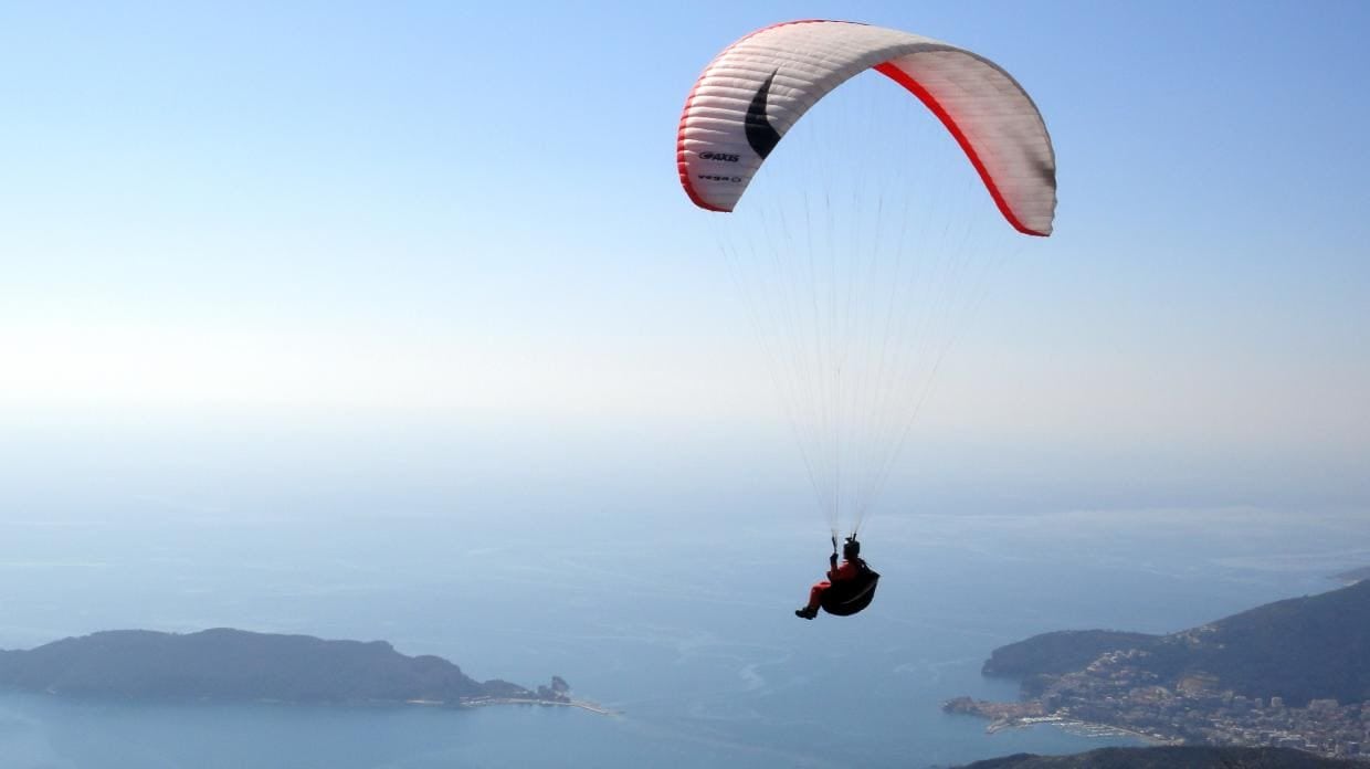 Tandem paragliding above the Montenegro coast with instructor and passenger in flight